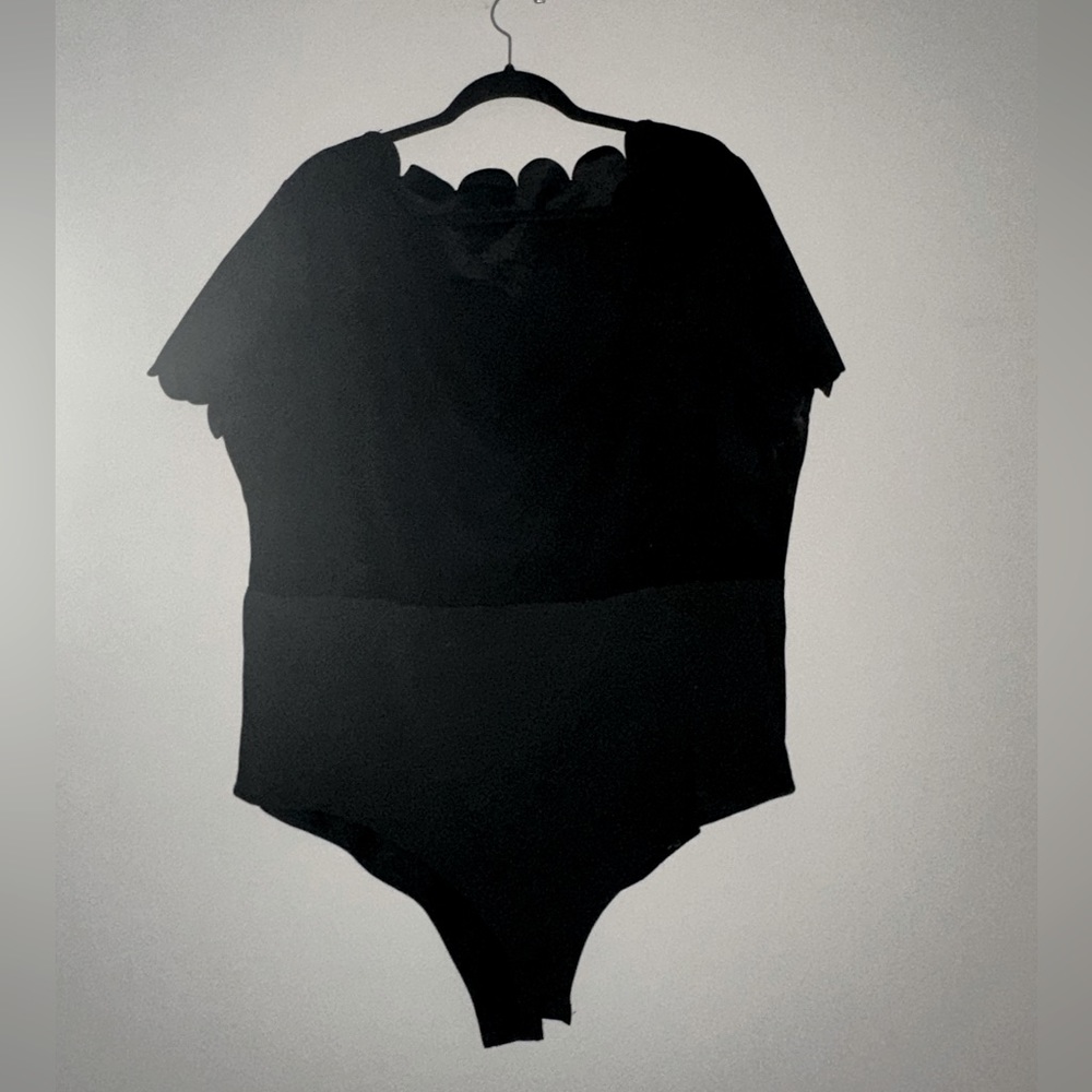 Black short sleeve body suit. Scalloped neckline and scalloped sleeve detail
